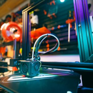 A close-up shot of a 3D printer in a vibrant and modern workshop environment.