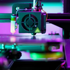 A neon-lit 3D printer operating, showcasing advanced technology and engineering.