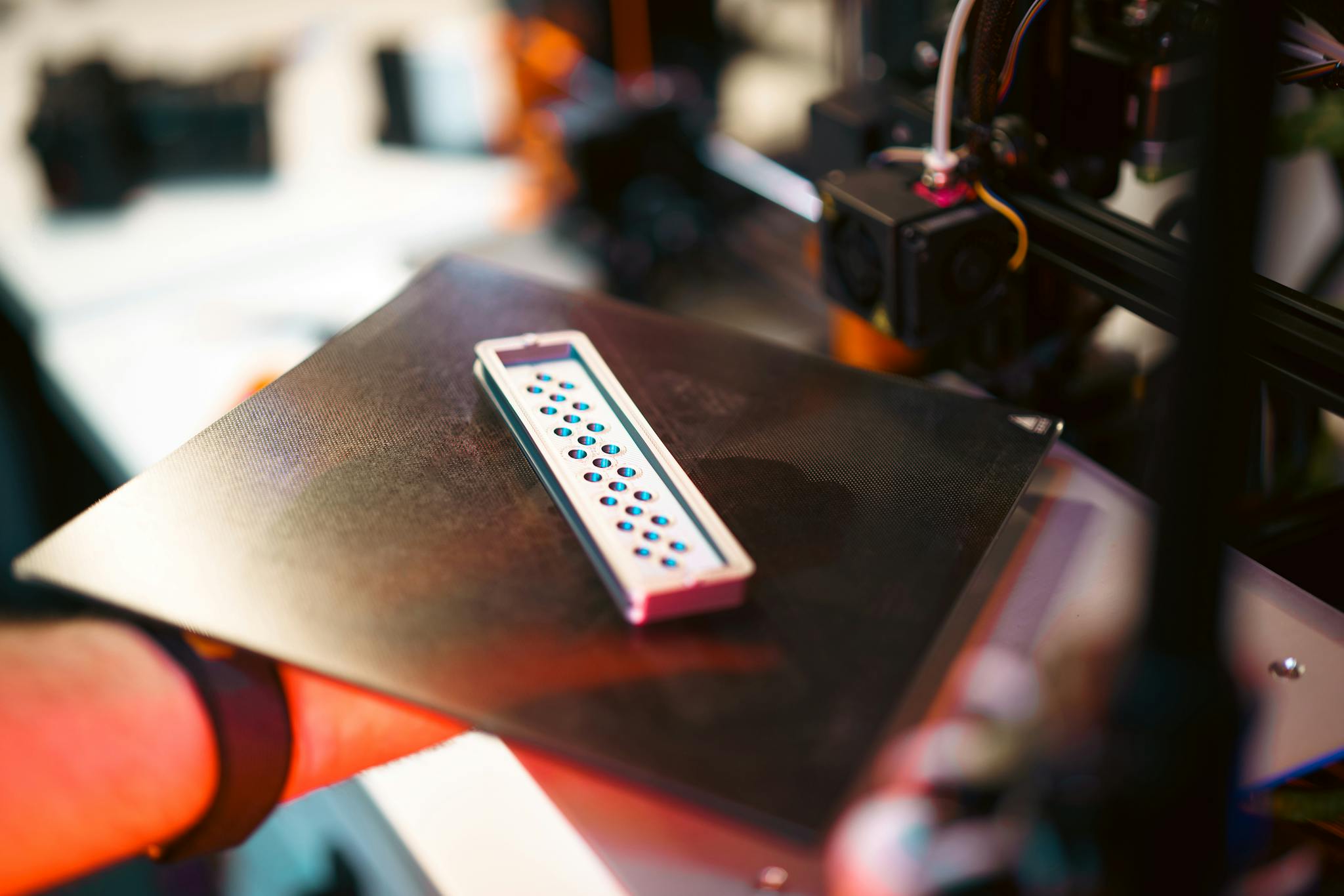 Close-up of a 3D printed part on an industrial printer in a workshop setting.