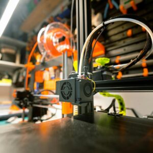 Close-up of a 3D printer in a workshop with visible tools and spool.