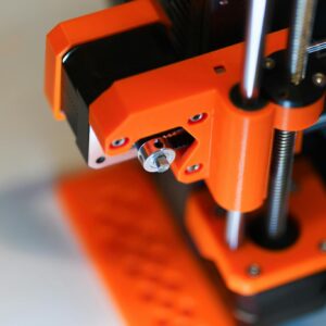 Detailed view of an orange 3D printer element with focus on mechanical parts.
